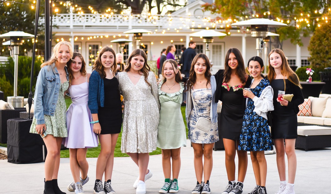 Group of friends celebrating outdoors at dusk under string lights