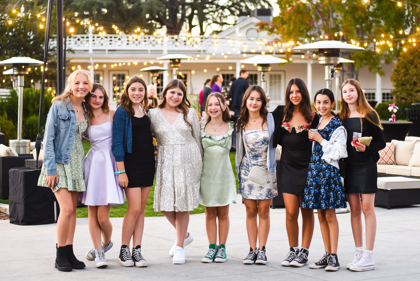 Group of friends celebrating outdoors at dusk under string lights