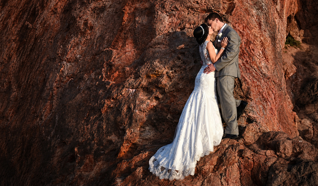 Bride and groom embracing on a sunlit cliffside
